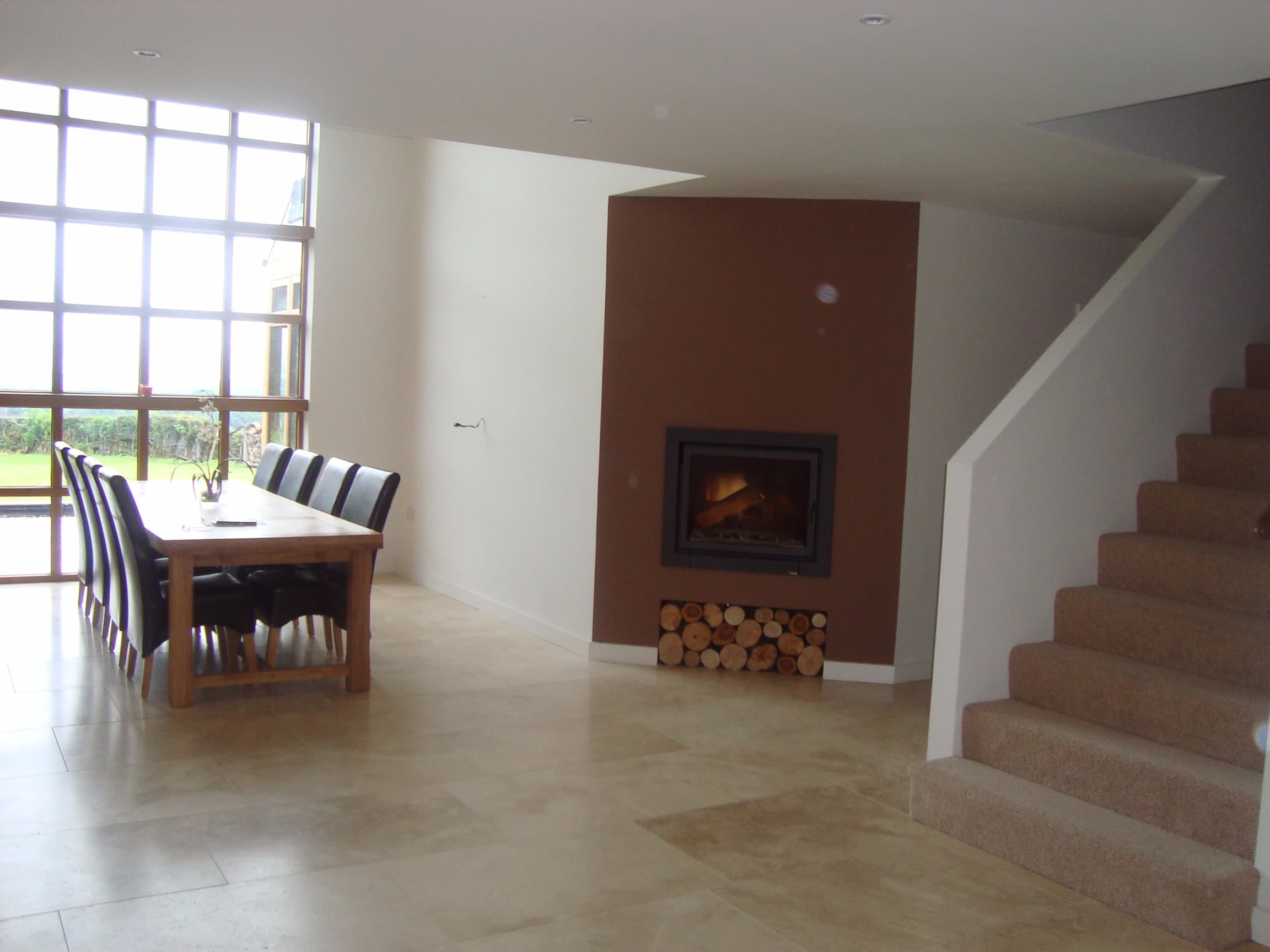 Double-height dining hall with a feature fireplace and open staircase